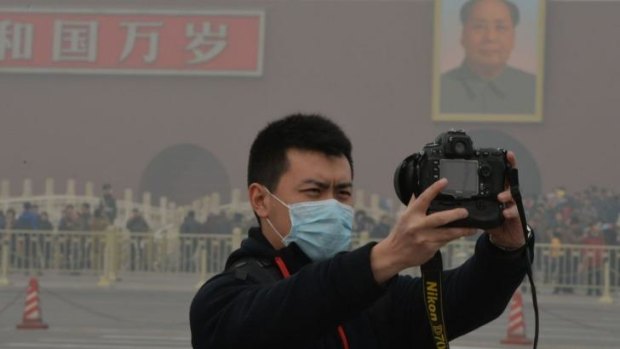 A Chinese tourist takes a selfie against a backdrop of heavy air pollution in Tiananmen Square.