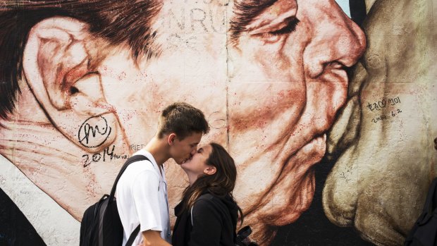 Life imitates art: A couple kiss in front of Russian painter Dimitri Vrubel's most famous work My God, help me to survive this deadly love on a section of the former Berlin Wall at the East Side Gallery in Berlin. 