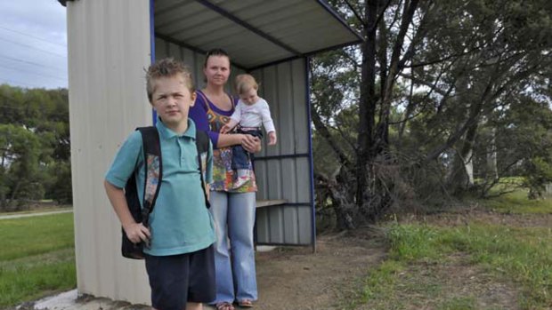 Faced with a daily trip of three hours, Brodie Suttie, 9, waits at the bus stop with his mother, Amanda Davey, and sister Charlotte, 1.