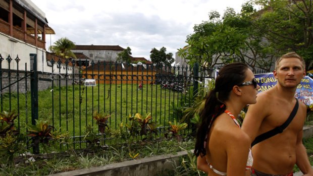 Tourists walk past the site of the old Sari Club which was destroyed in the 2002 Bali bombings and is being used as a temporary motor bike park.