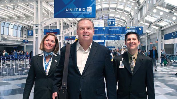 Tom Stuker, centre, the first customer ever to fly 10 million miles with United Airlines, walks through Chicago O'Hare International Airport with United employees.