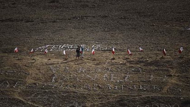 Relatives stand among Chilean flags with the names of the 33 miners trapped at the San Jose mine.