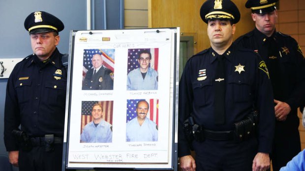 Police stand by the photo of the dead and injured firefighters during a news conference.