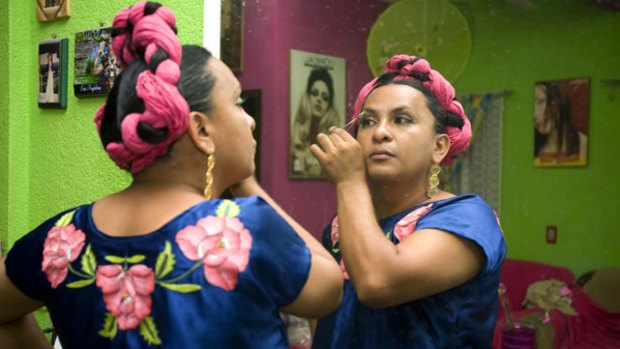 A man, dressed in the traditional costume of a Zapotec woman, plucks his eyebrows in preparation for the festival.