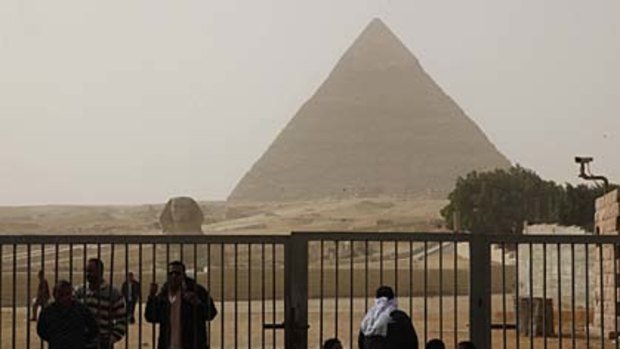 Egyptian tourist guides and security sit near the Pyramids, in Giza. The pyramids are closed to tourists.