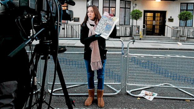 A broadcast journalist holds up a copy of a daily newspaper outside the King Edward VII hospital in central London after nurse Jacintha Saldanha was found dead the previous day.