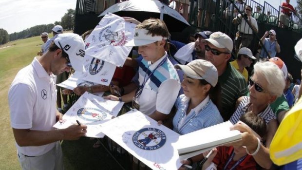Adam Scott signs large cards after a practice round.