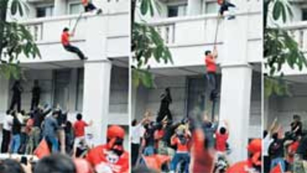 Thai Red Shirt protesters support Red Shirt leader Arisman Pongruangrong as he scales down the wall.