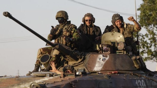 Ukrainian servicemen ride on an armoured vehicle in Mariupol following the ceasefire.
