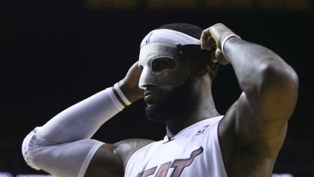 Miami Heat's LeBron James adjusts his protective mask during the first half against the Charlotte Bobcats.