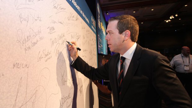 AWU chief Paul Howes signs his name to a pledge to stop Tony Abbott in his tracks at the union's conference in Queensland. Picture: AWU