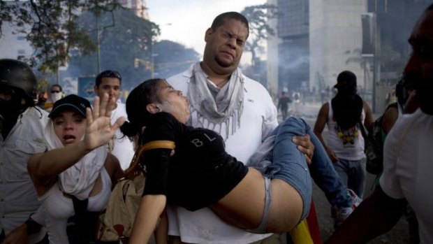 A man carries a woman affected by tear gas  at an anti-government demonstration in Caracas on February 22.