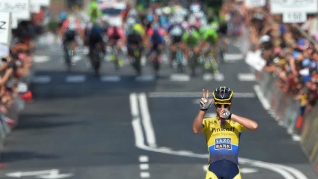 Michael Rogers of Canberra claims the stage victory as the peloton looms behind him.