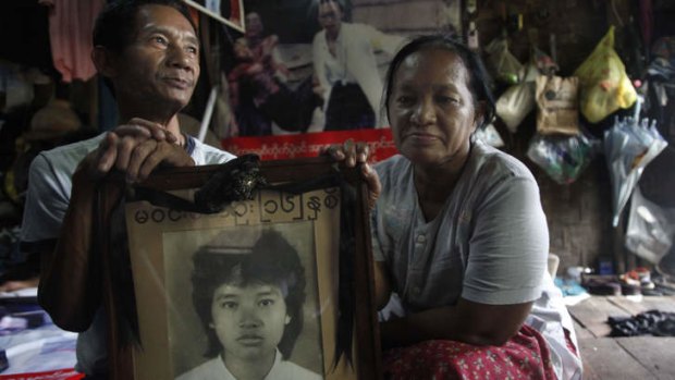 Win Kyu, left, and his wife Khin Htay Win hold a portrait of their 16-year-old daughter Win Maw Oo, who was killed during the 1988 protests. The photo behind them of their badly injured daughter came to symbolise the brutality of the crackdown.