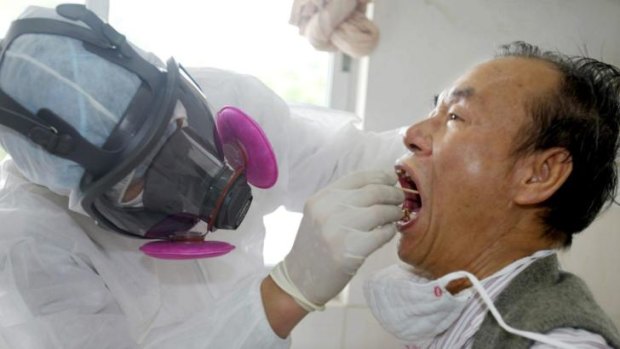 A medical worker, wearing full protective suit, examines a man in an earlier outbreak scare in China in 2003.