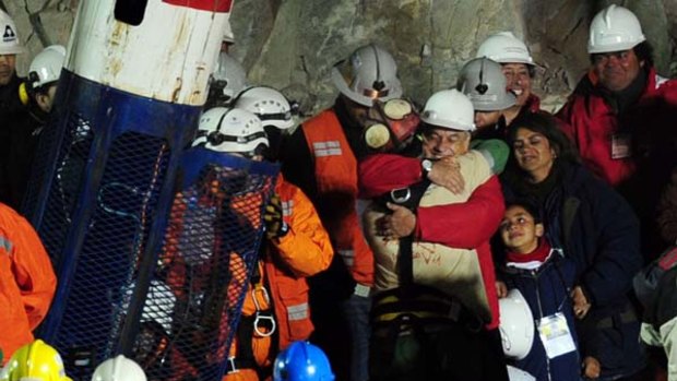 Seeing the light ... Florencio Avalos, the first miner to be freed, hugs the Chilean President, Sebastian Pinera, seconds after stepping out of the Fenix capsule that brought him to the surface. His son Bairon, 7, and his wife, Monica, look on.