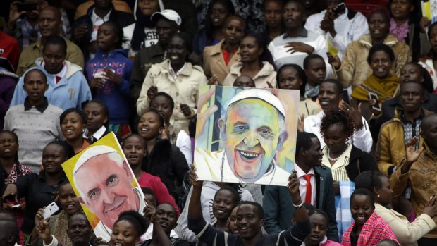 Youths hold images of Pope Francis prior to his arrival at a stadium in Nairobi.