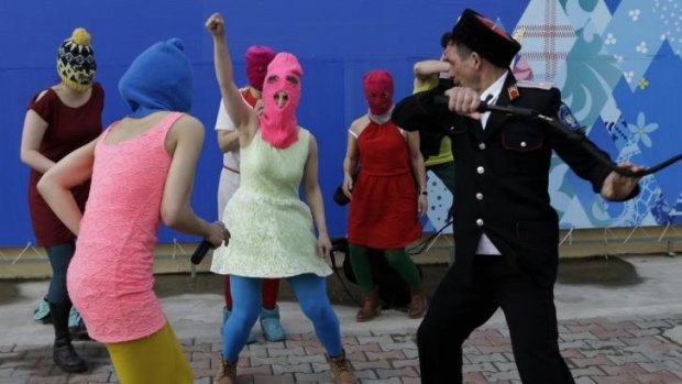 A Cossack about to attack Nadezhda Tolokonnikova (wearing the blue balaclava) as Maria Alekhina holds her fist high.