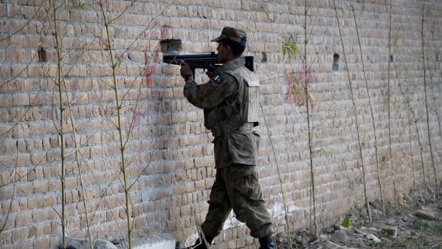 A Pakistani soldier take up position behind a wall outside a besieged mosque in Pakistan's garrison city Rawalpindi where 35 people were killed in a suicide attack.