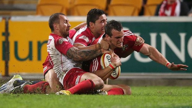 Reds playmaker Quade Cooper collars Sam Warburton of the Lions just short of the try line at Suncorp Stadium.