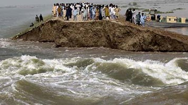 Pakistani villagers stand on the remains of an embankment washed away by heavy flooding in Thatta.