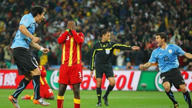 Uruguay players start celebrating while Asamoah Gyan, of Ghana, shows his devastation at missing a late penalty kick in extra time of the quarter-final at the Soccer City stadium.