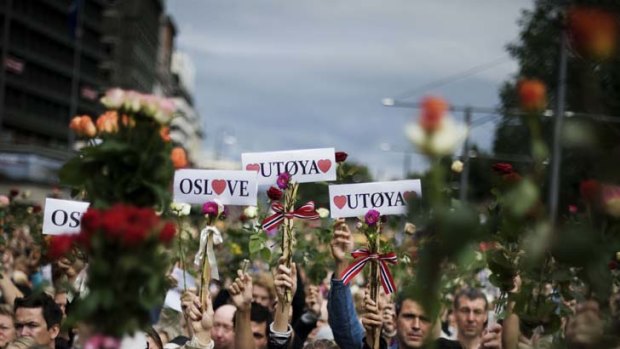 In memoriam ... people hold roses aloft as thousands mass outside the City Hall in the Norwegian capital of Oslo on Monday to remember the victims of last week's twin attacks.