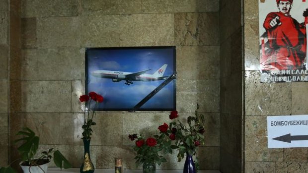 Flowers and a candle sit underneath a poster of a Malaysian plane on the wall in the Donetsk Administration building in the self-proclaimed Donetsk People's Republic. 