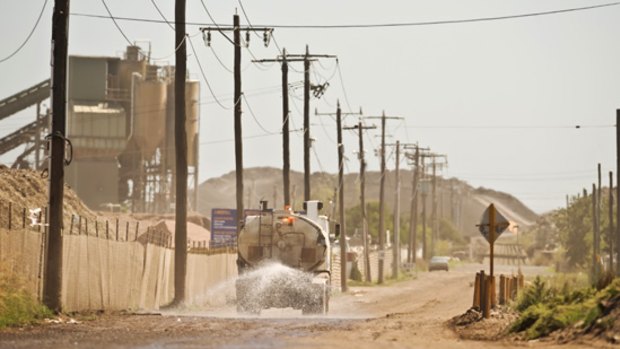 A water truck wetting a dusty road in an industrial area in Brooklyn.