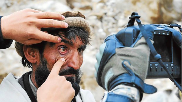 An Afghan has his eyelids pulled apart as a US soldier takes an image of his retina.