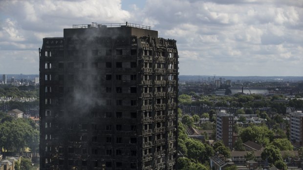 Debris hangs from the blackened exterior of Grenfell Tower in London.
