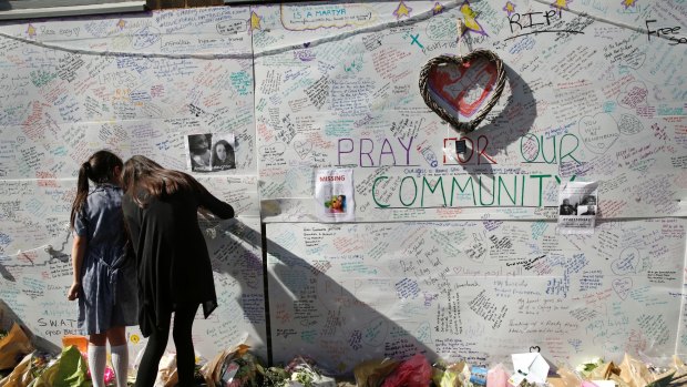 People write messages on a wall for the victims and in support for those affected by the Grenfell Tower fire.