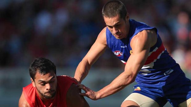 Gold Coast's Karmichael Hunt and the Western Bulldogs' Daniel Giansiracusa tussle for the ball at Metricon Stadium.