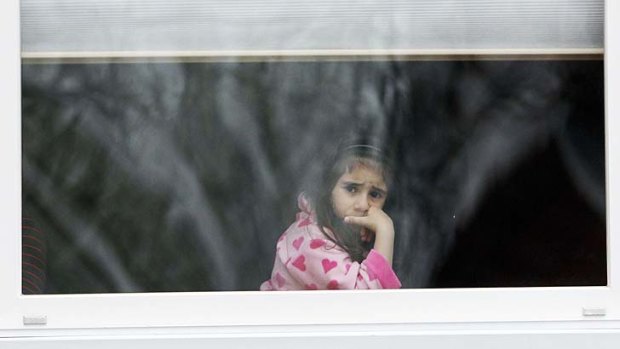 Waiting game: a girl looks out her window as law enforcement searches for Dzhokar Tsarnaev.