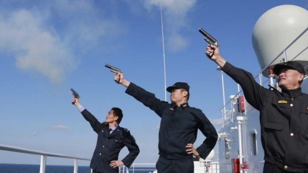 Chinese personnel fire their pistols to signal the start of a naval exercise in the East China Sea.