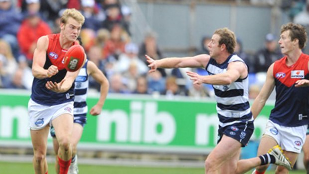 Melbourne youngster Jack Watts handballs before Geelong's Steve Johnson can tackle.