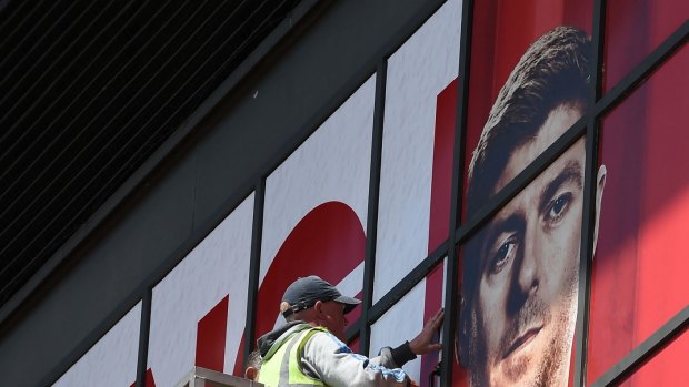 Workmen paste a poster over Liverpool's English midfielder Steven Gerrard as they replace sections of a mural outside The Kop stand at Anfield.