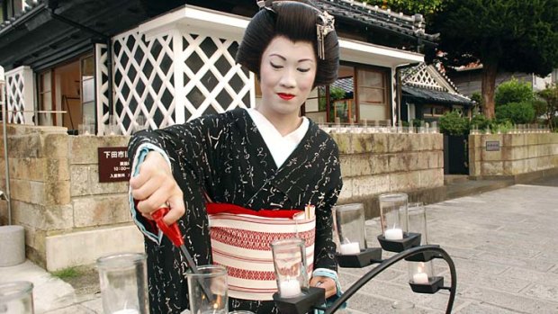Chinese geisha trainee Rinka, born as Zhang Xue in Shenyang, China, lights candles before a summer festival near her geisha school building in the port town of Shimoda.