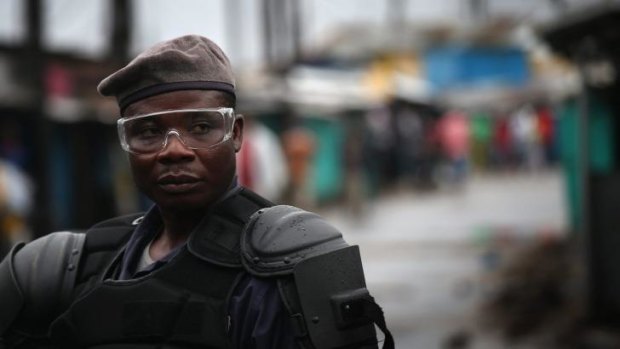 A Liberian police officer stands guard on the second day of the government's Ebola quarantine on a neighborhood in Monrovia, Liberia.