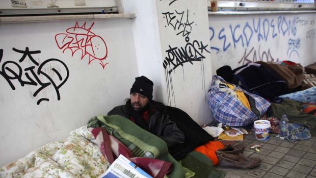 Doing it tough ... homeless men sleep rough beneath a graffiti-covered wall in an Athens train station.