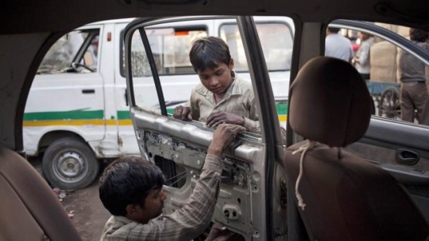 Child labour: Indian boys fix a car at a repair shop in New Delhi, India.