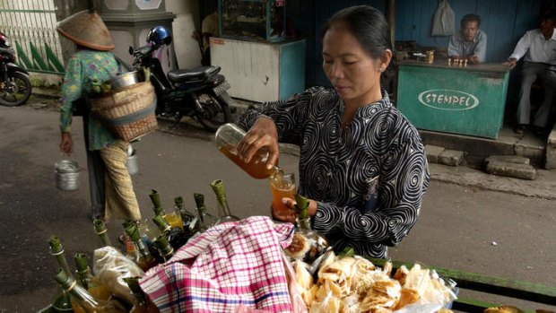 A vendor pours her jamu.