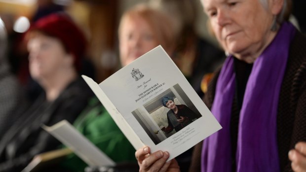 Mourners read from the order of service at the funeral for Joan Kirner.