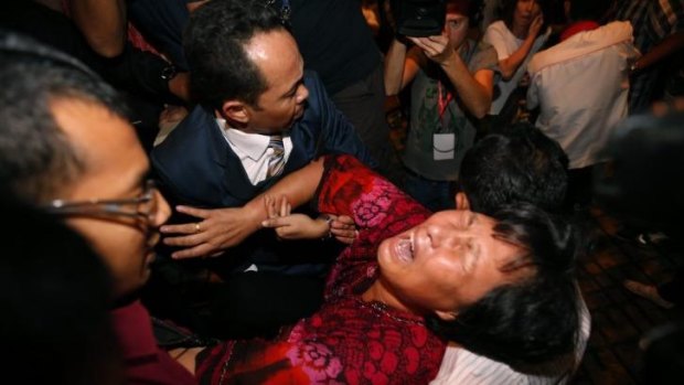Liu Guiqiu is carried out by security officials as she protests before a press conference about the missing Malaysia Airlines flight.