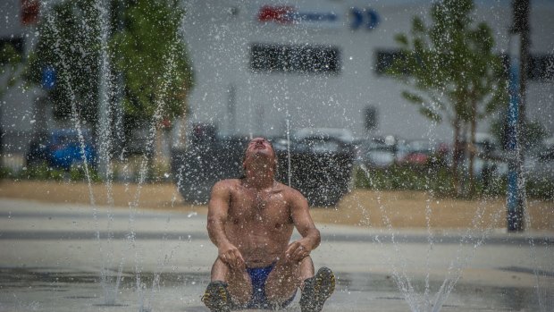 Craig Davis takes advantage of the new sprinkler fountain in Queanbeyan to cool off during the Summer hot spell. Photo by Karleen Minney.