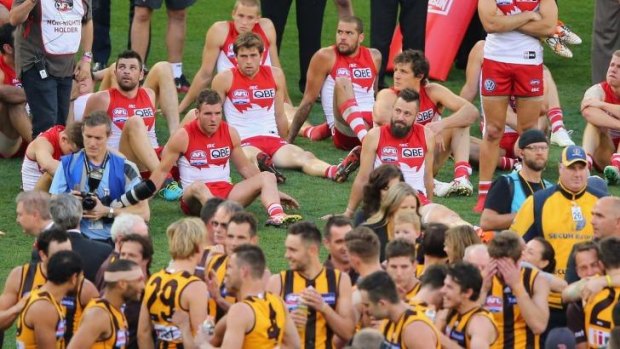 Two halves: Sydney players look on as Hawthorn celebrates its victory. 