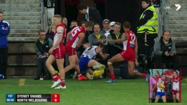 Down and out: Luke McDonald is slung into officials seated between the interchange benches by Kieren Jack. 