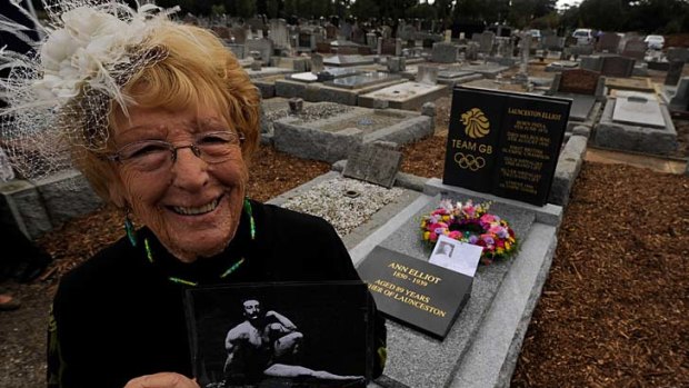 Ann Elliot Smith holds a picture of her grandfather Launceston Elliott, Britain's first Olympic gold medalist, after the unveiling of a plaque at his grave at Fawkner Cemetery.