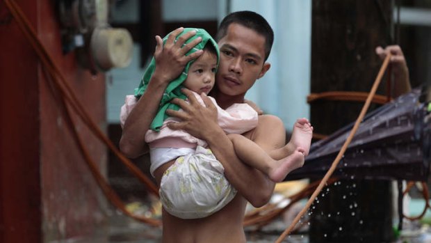 A Filipino man carries his son across a flooded street as they evacuate to higher grounds in Las Pinas, south of Manila.