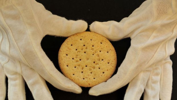 A  Huntley and Palmers biscuit from Ernest Shackleton's Nimrod store is held by a Christie's employee.